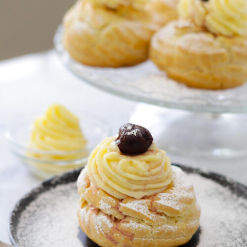 St Joseph's pastry in a close up, with pastry cream and amarena on top. In the background more zeppole.