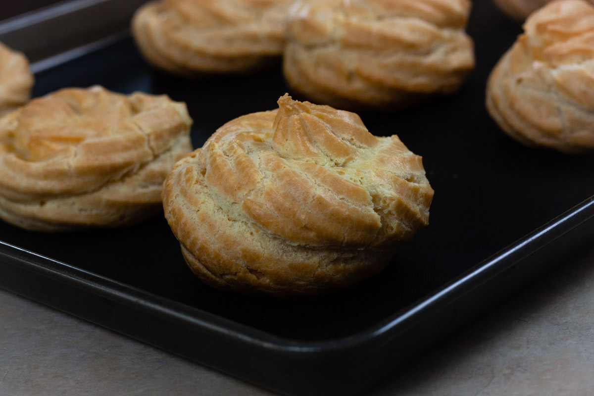 Oven baked zeppole on a oven sheet.