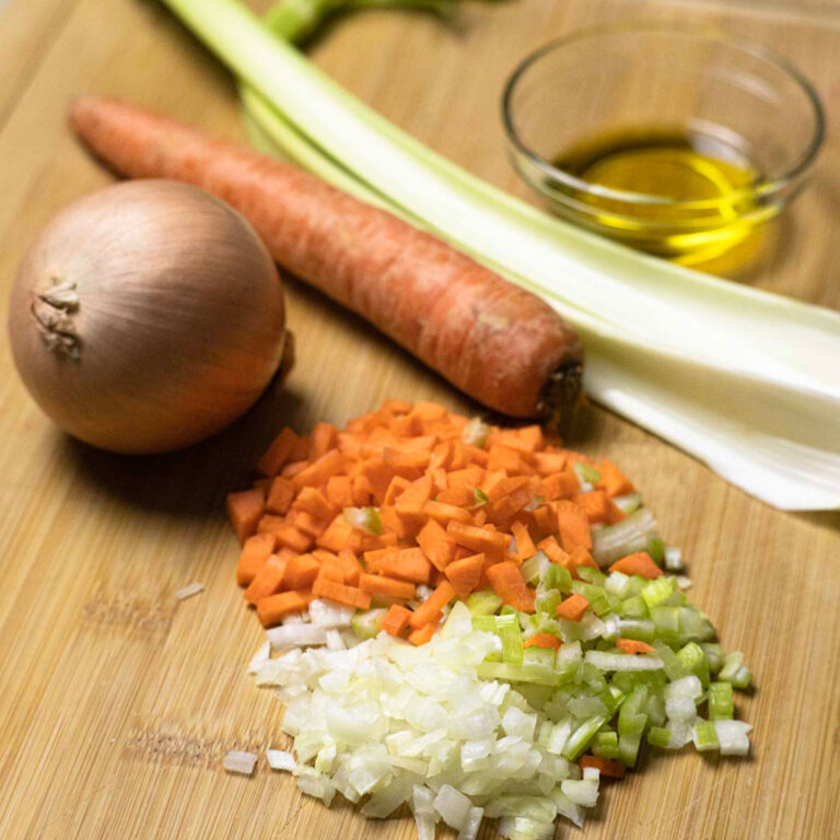 Soffritto arranged on a chopping board with ingredients in the background.