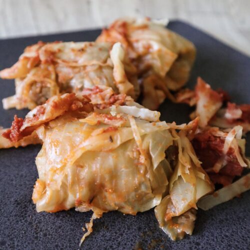 Italian cabbage rolls featured picture of the rolls on the dark black plate.