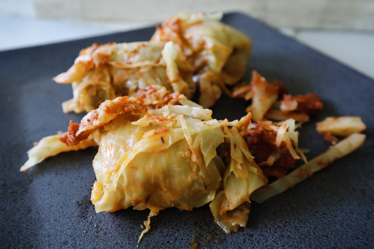 Introductive photo of the Italian cabbage rolls on a dark black plate, close-up shot of the rolls.