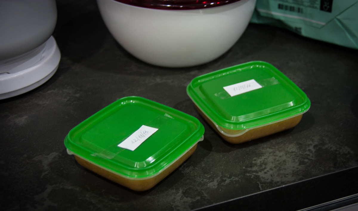 Two small labeled containers of homemade brodo vegetale. Two small labeled containers of homemade brodo vegetale stored in the freezer.