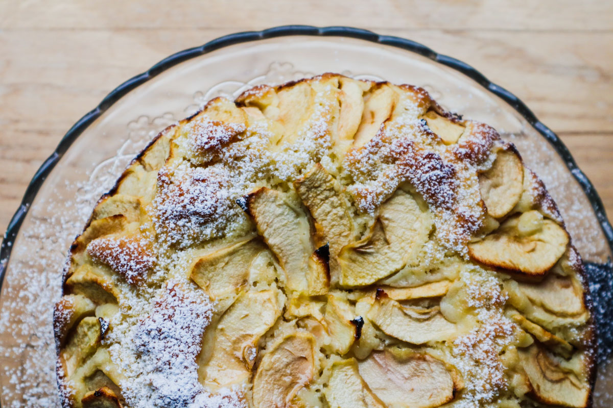Overhead view of the Italian apple cake with its apple‑circle pattern and a light dusting of powdered sugar.