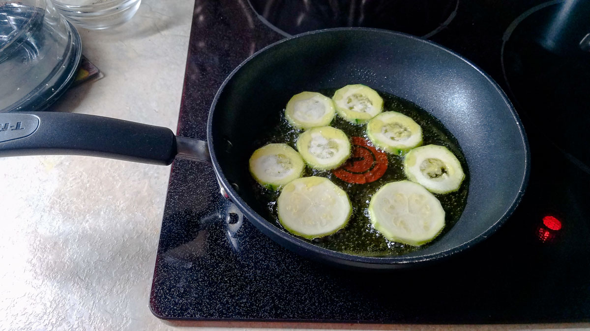 Green zucchini frying in a pan for pasta with fried zucchini.