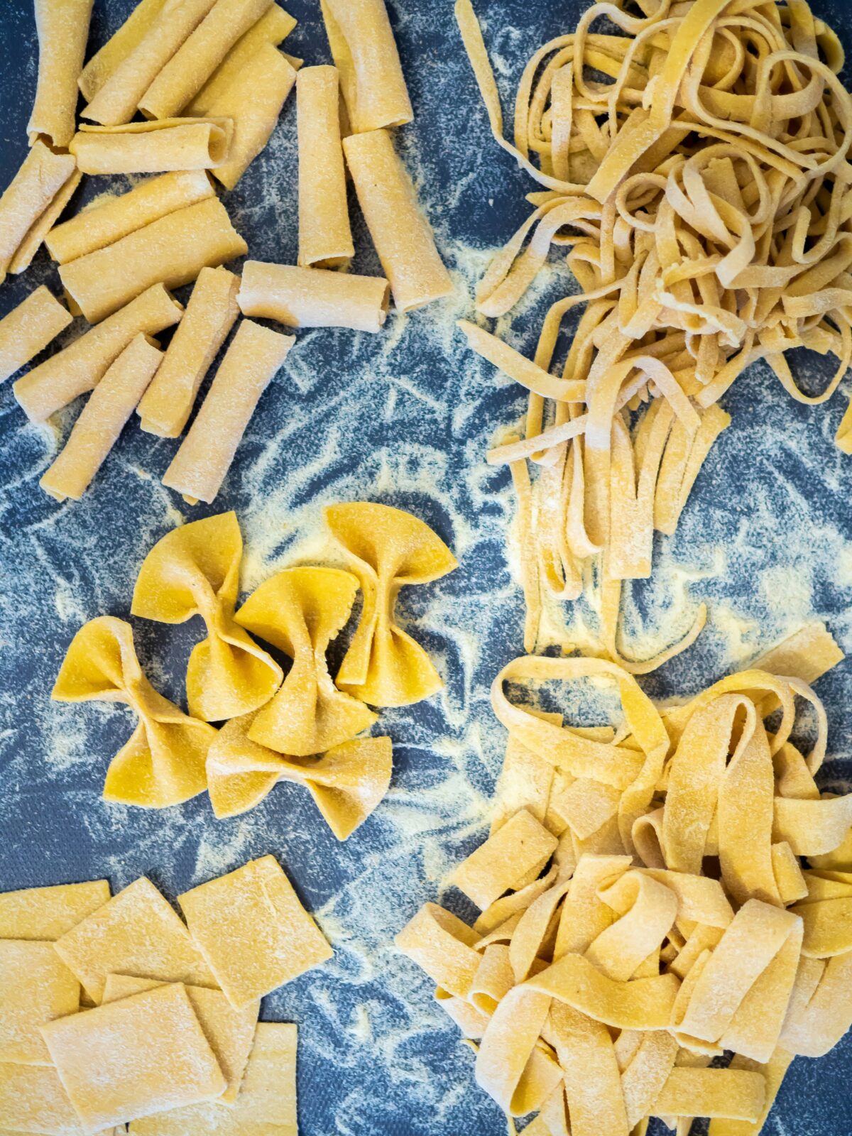 Fresh pasta in long and short shape on a blue tablecloth.