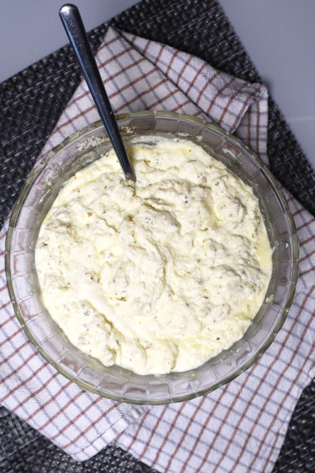 Overhead view of ricotta filling with Parmigiano Reggiano, eggs, breadcrumbs, and diced cooked ham in a glass bowl.
